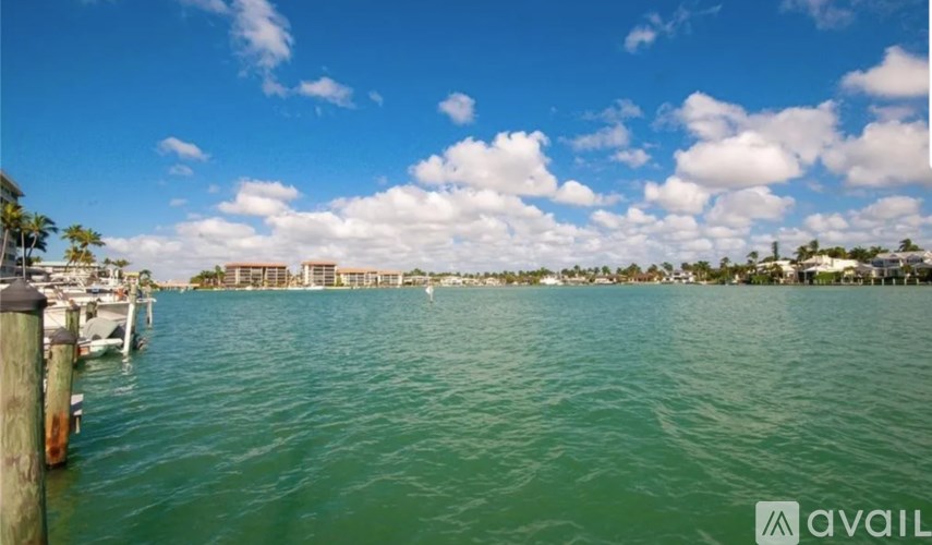 A body of water with boats docked and buildings in the background.
