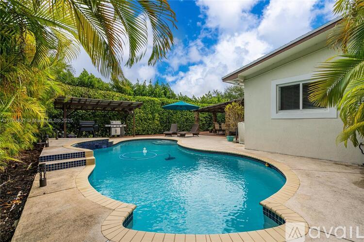 A swimming pool surrounded by palm trees and a house.