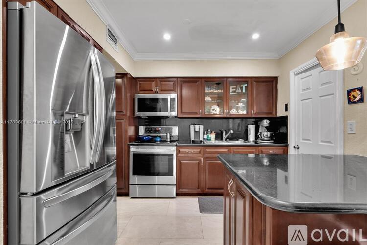 A kitchen with a stainless steel refrigerator and wooden cabinets.