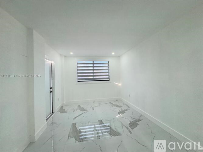 A spacious room with a marble floor and a window with blinds.