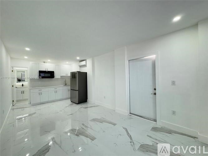 A kitchen with white cabinets and a black fridge.