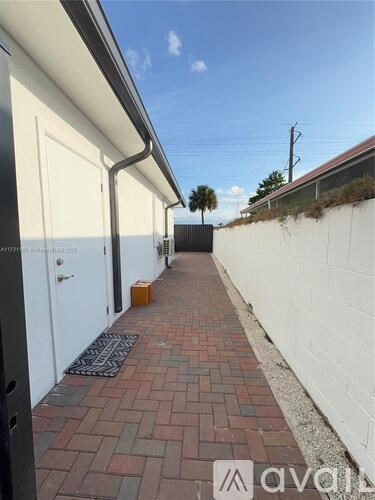 A long brick pathway leads to a white door.