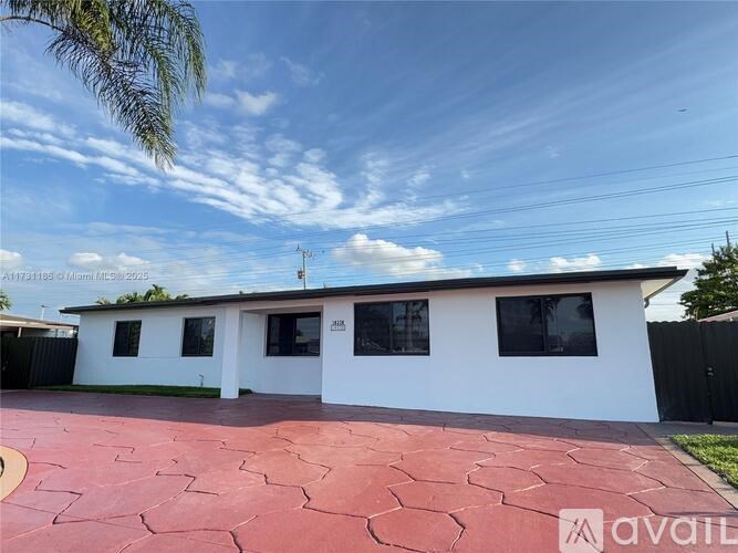 A white house with a red tiled driveway is for sale.