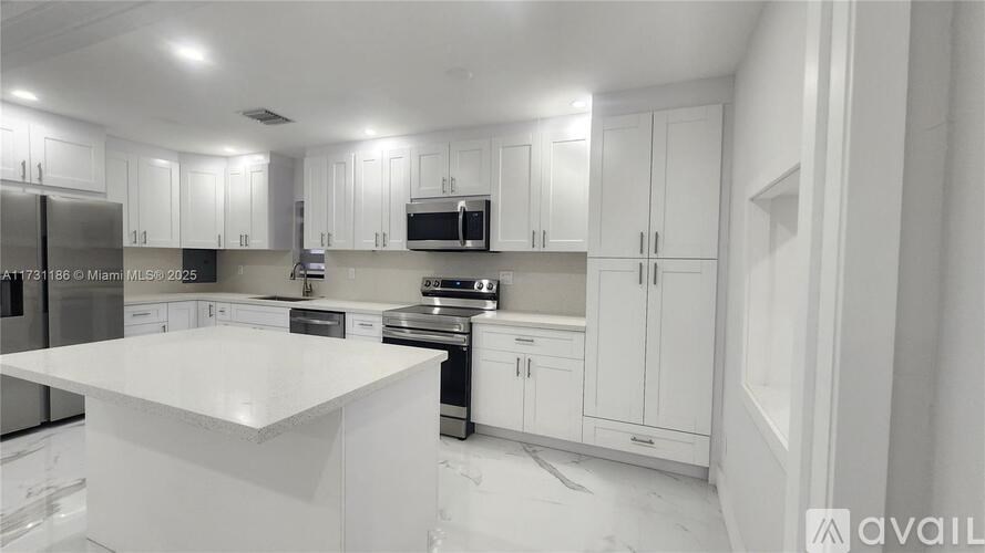 A modern kitchen with white cabinets and appliances.