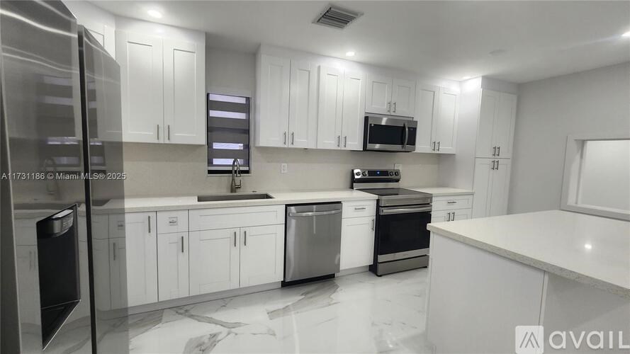 A modern kitchen with white cabinets and stainless steel appliances.