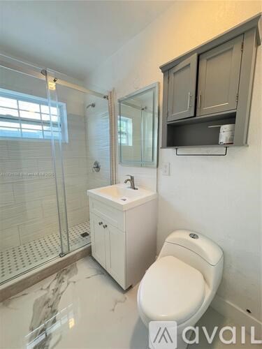 A white toilet sits in a bathroom with a walk-in shower.