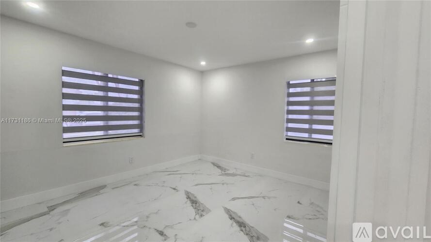 A room with a marble floor and two windows with blinds.