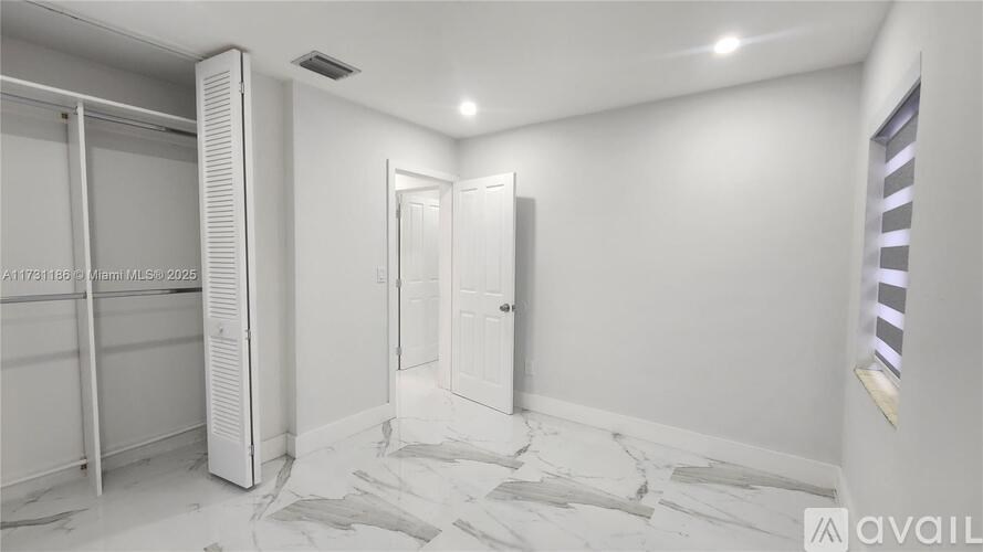A white bathroom with a marble floor and a walk-in shower.