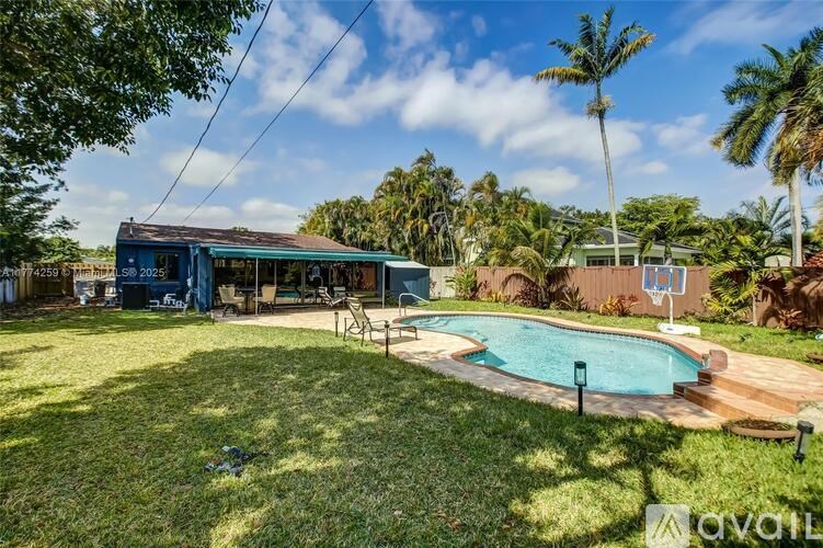 A pool surrounded by a grassy area with a house in the background.