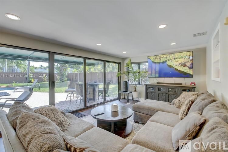 A living room with a large couch and a flat screen TV mounted on the wall.