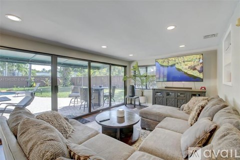 A living room with a large couch and a flat screen TV mounted on the wall.