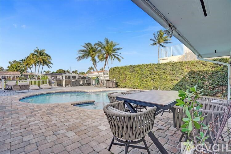A patio with a table and chairs overlooking a pool.