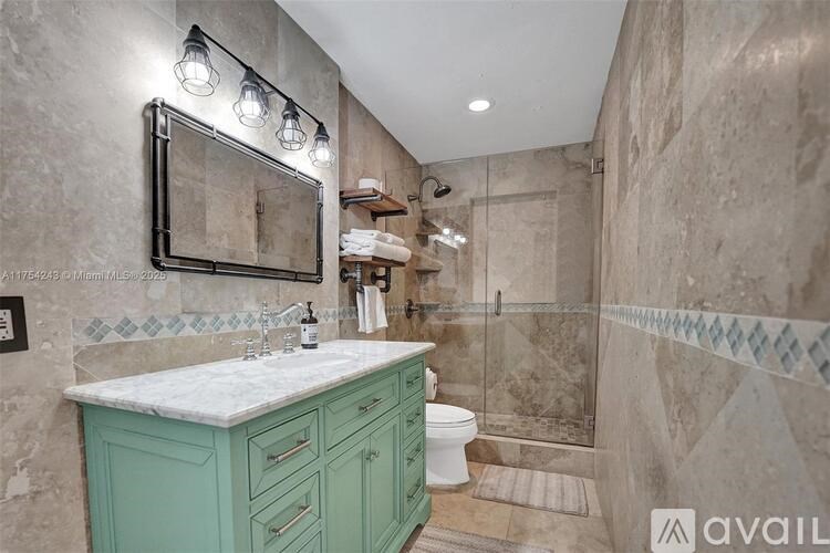 A bathroom with a green vanity and a walk-in shower.