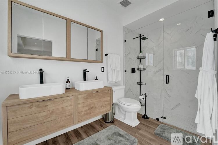 A bathroom with a wooden vanity and a walk-in shower.