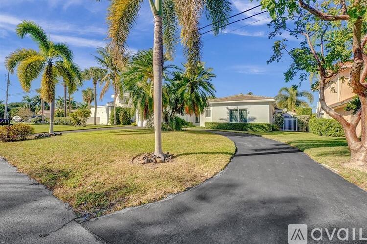 A residential area with a house, palm trees, and a driveway.