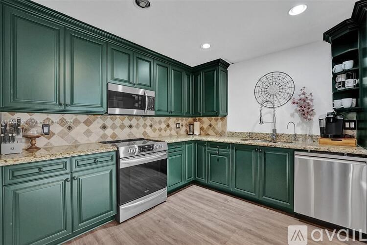 A kitchen with green cabinets and a white wall.