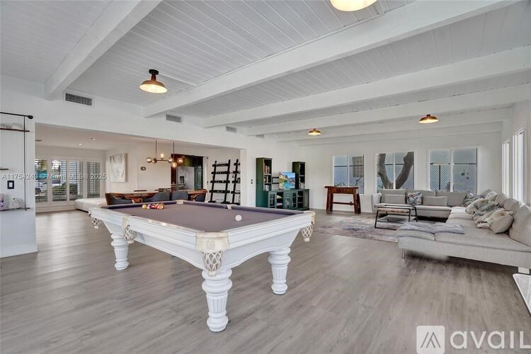A spacious living room with a pool table and a couch.
