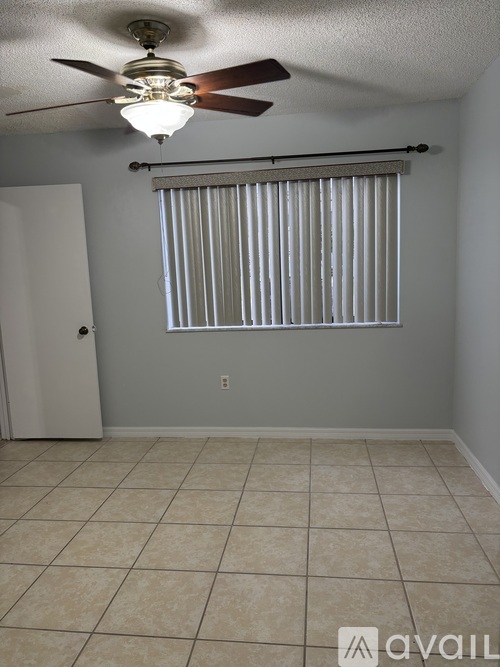 A room with a ceiling fan and a window with blinds.
