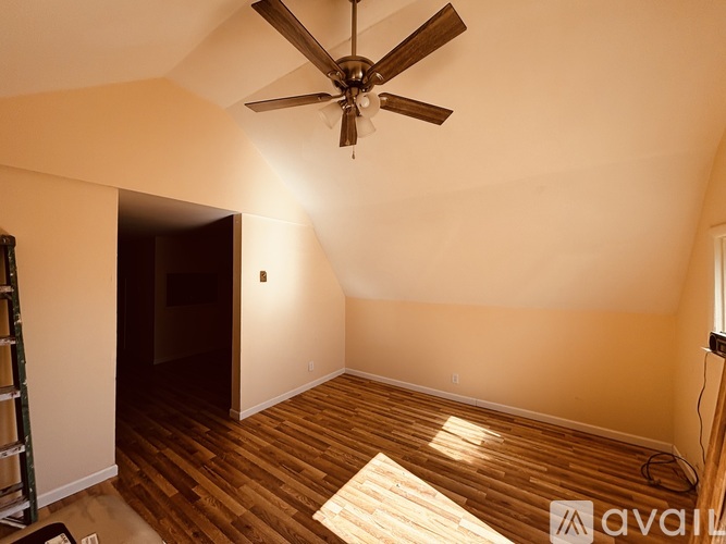 A room with a ceiling fan and wooden flooring.