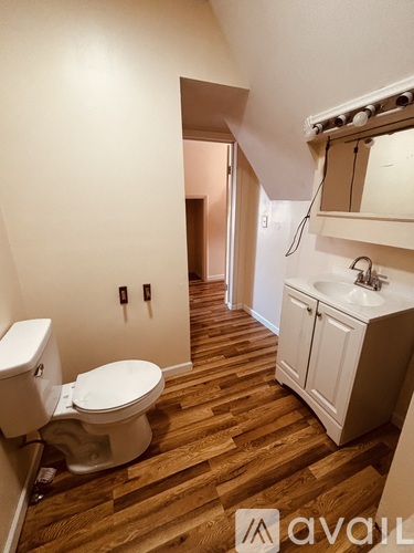 A bathroom with a toilet, sink and wooden floor.