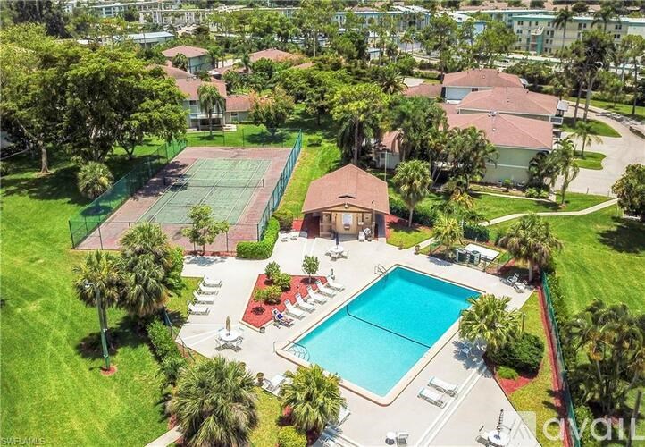 A large swimming pool surrounded by a red fence and palm trees.