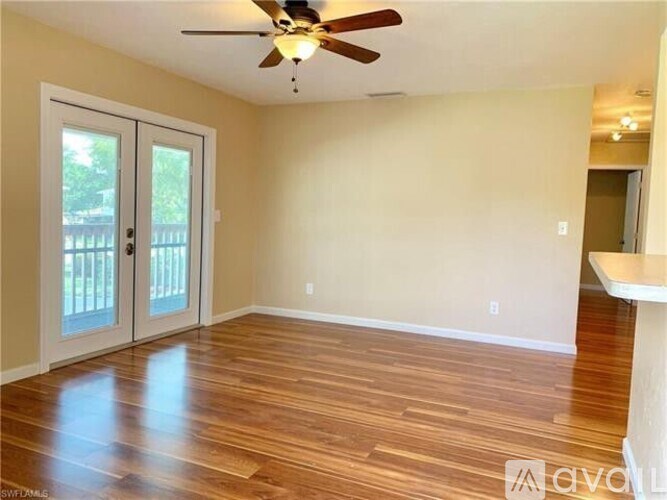 A room with a ceiling fan and sliding glass doors.
