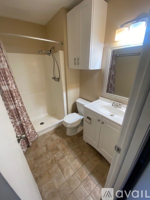 A small bathroom with a toilet, sink, and shower.