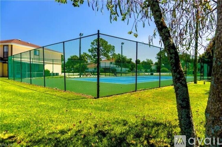 A tennis court is enclosed by a green fence.