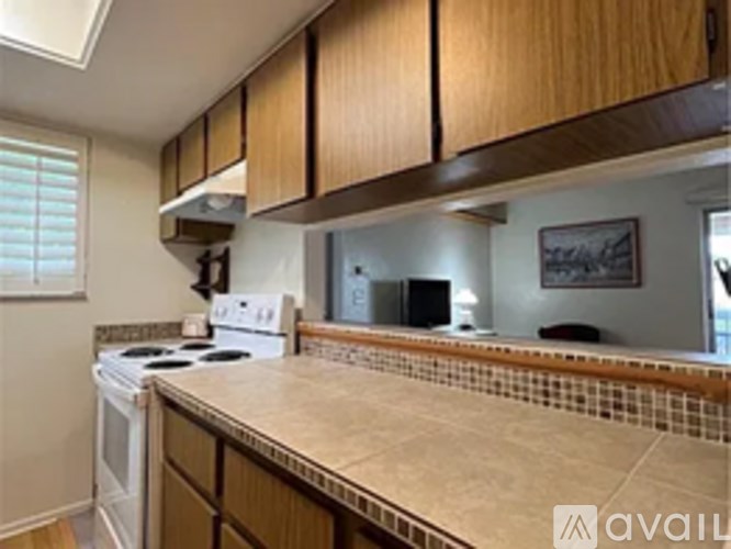 A kitchen with a white stove top oven and a tiled counter top.