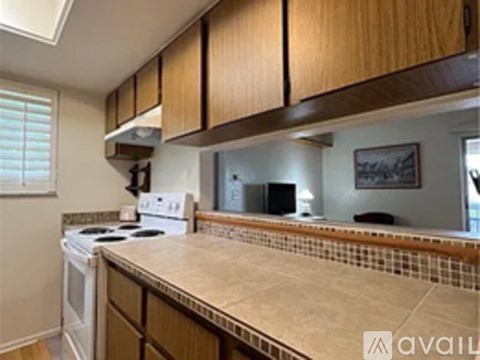 A kitchen with a white stove top oven and a tiled counter top.