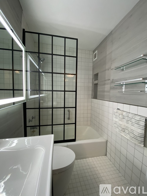 A modern bathroom with a glass block shower and a white bathtub.