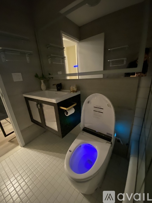 A toilet with a blue light on the lid in a bathroom.