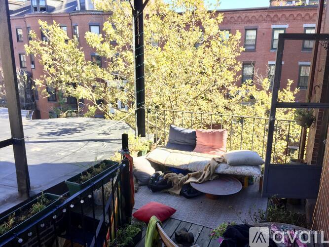 A balcony with a couch and a table is surrounded by a metal fence.