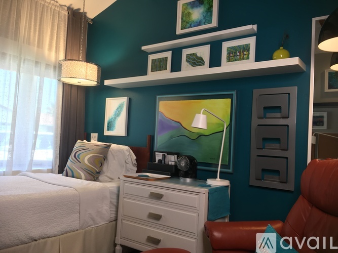 A bedroom with a bed, nightstand, and a painting on the wall.