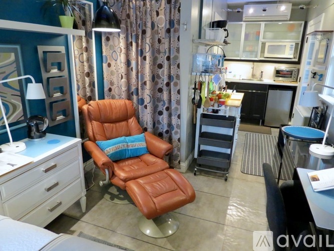 A brown leather chair with a blue cushion is in the center of a room with a blue wall and a white cabinet.