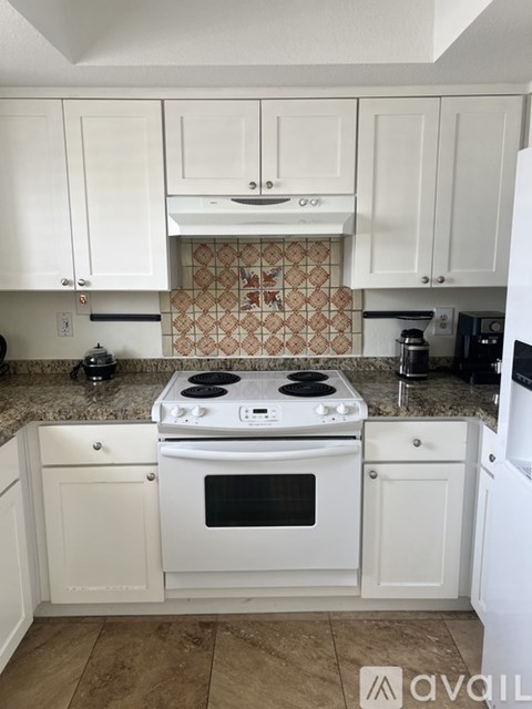 A kitchen with white cabinets and a tiled backsplash.