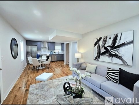 A modern living room with a grey couch and a large abstract painting on the wall.