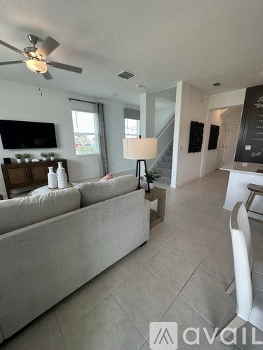 A living room with a grey couch and a television on the wall.