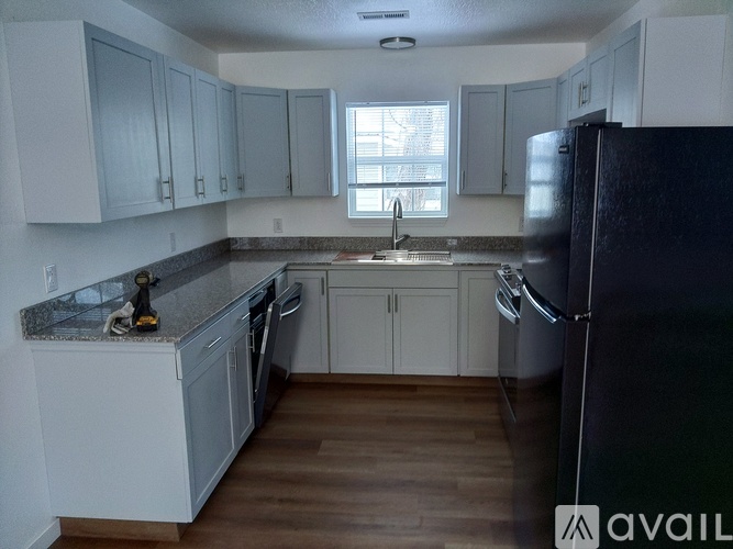 A kitchen with white cabinets and a black refrigerator.