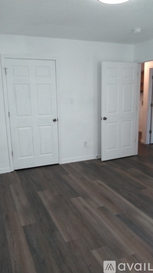 A room with two white doors and wooden flooring.