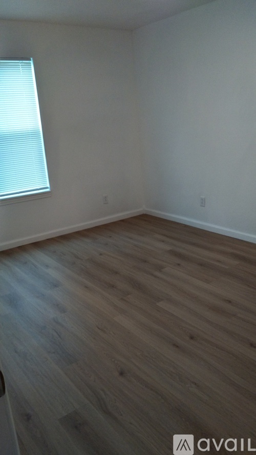 A room with wooden flooring and a window with blinds.