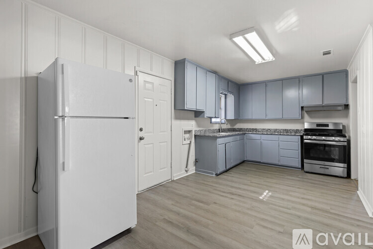 A kitchen with a white refrigerator and grey cabinets.