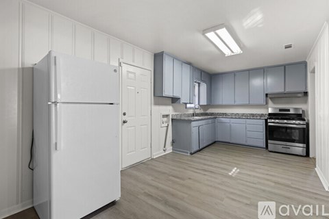 A kitchen with a white refrigerator and grey cabinets.