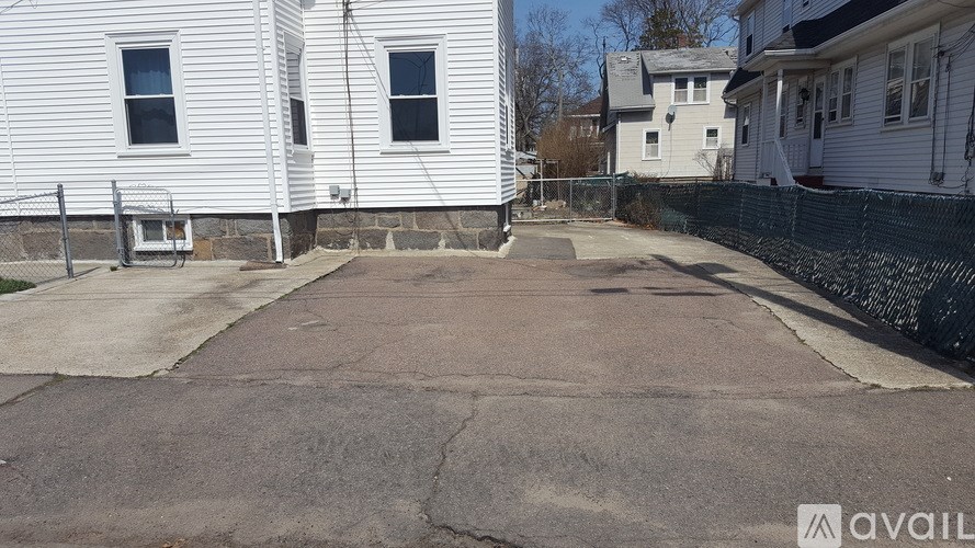 A white house with a black fence and a driveway in front.