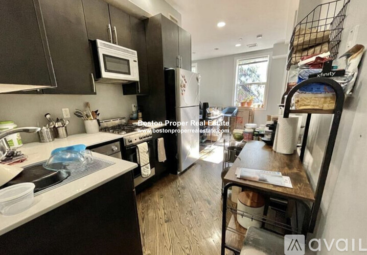 A kitchen with black cabinets and a white microwave.
