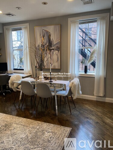A dining room with a table set for four and a painting on the wall.