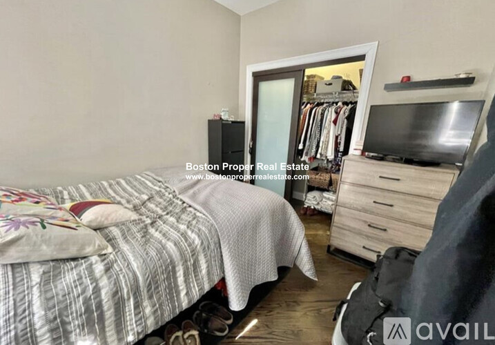 A bedroom with a bed, dresser, and a television.