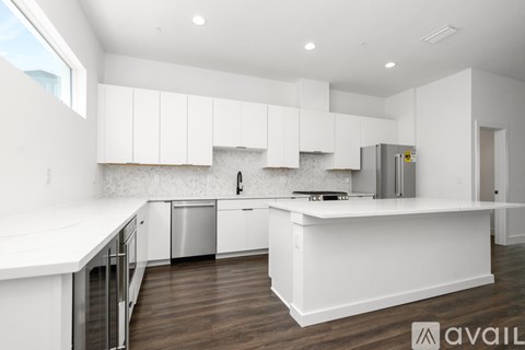A modern kitchen with white cabinets and a wooden floor.