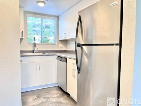 A kitchen with a stainless steel refrigerator and white cabinets.