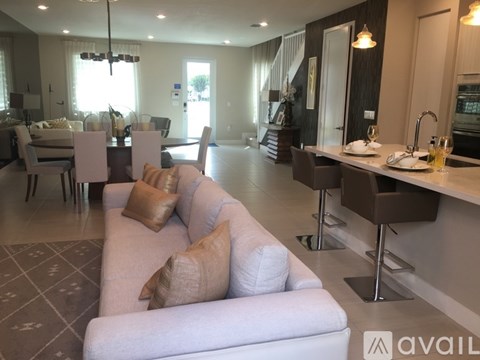 A modern living room with a grey couch and a dining table with chairs.